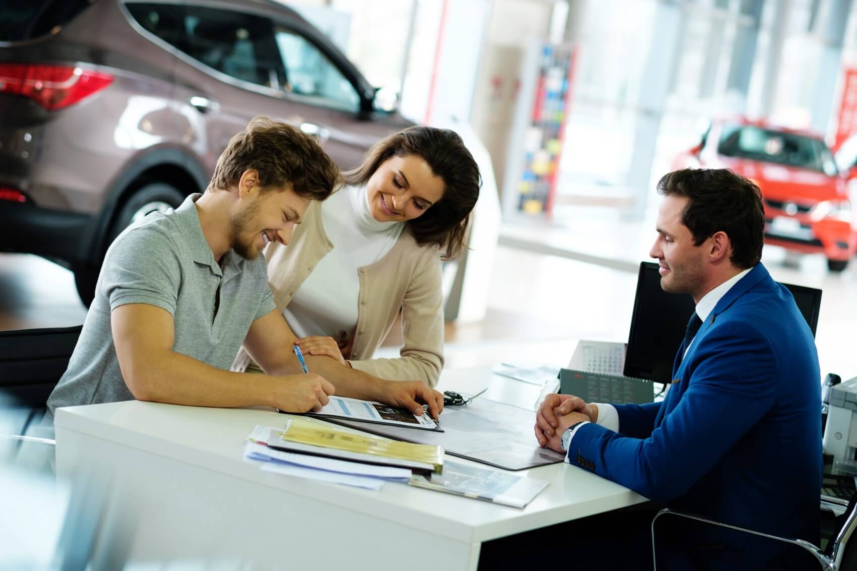 smiling couple talks to finance officer and signs chevy blazer paperwork